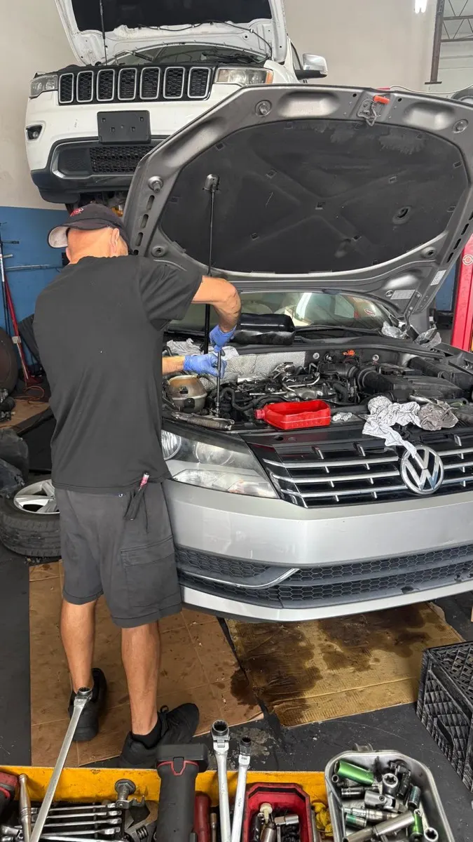 Mechanic working under the hood of a Volkswagen at the shop