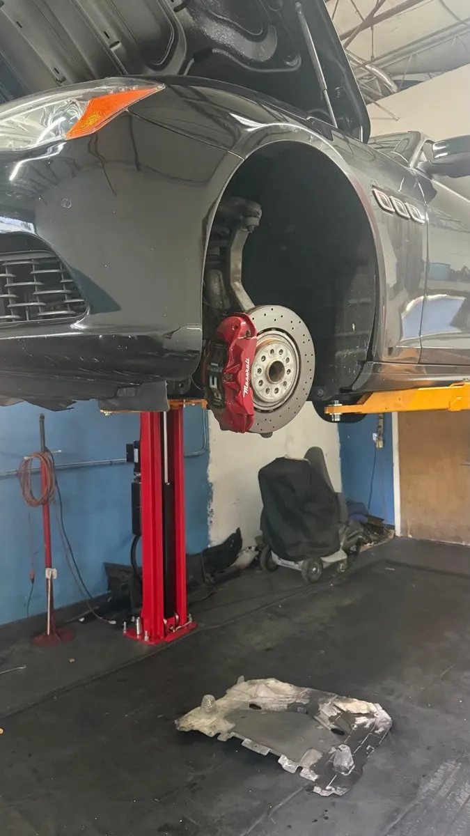 Maserati red brake caliper and drilled rotor during a brake service